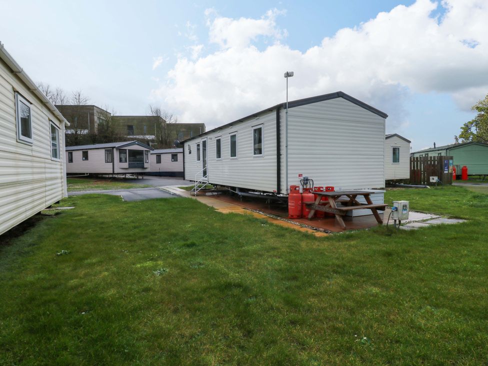 A caravan with a picnic table and gas bottles at Valley 36 in Kingsbridge