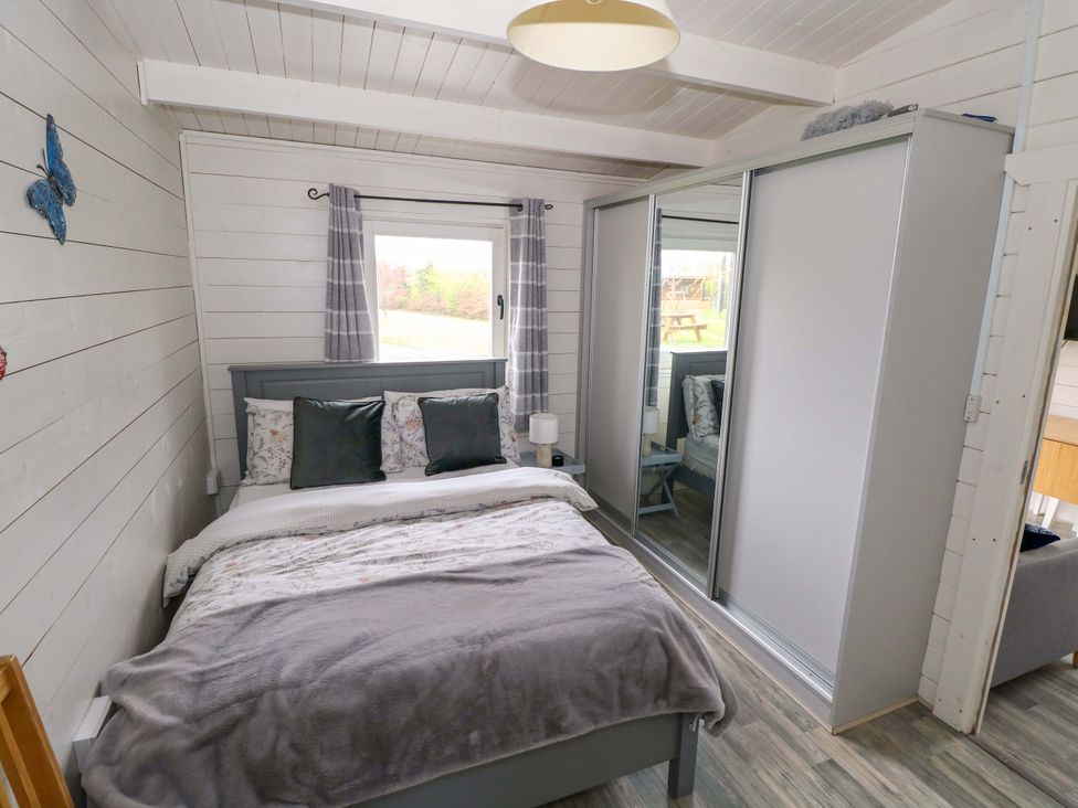 A bedroom with a bed and wardrobe at Nellies Log Cabin, Kilcogy