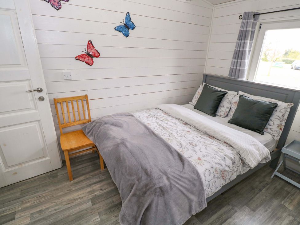 A bedroom with a bed and chair at Nellies Log Cabin in Kilcogy