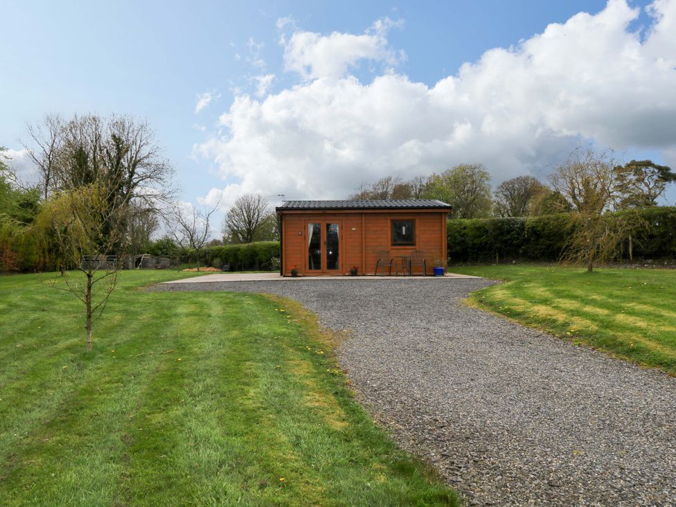 A log cabin with a gravel driveway in a garden at Nellies Log Cabin, Kilcogy