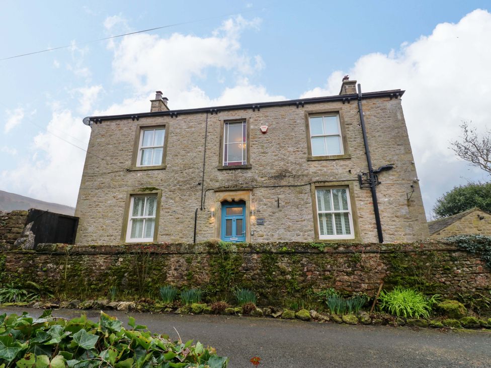 A house with stone walls and a blue door at Langcliffe House in Kettlewell
