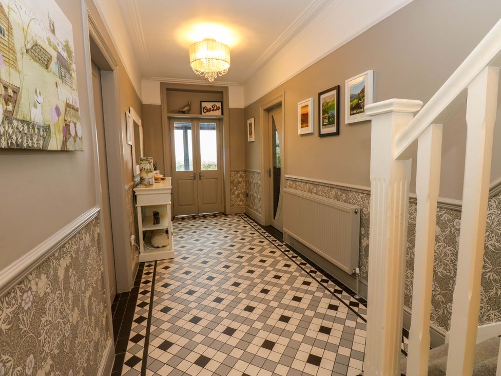 A hallway with a staircase and wall art at Langcliffe House in Kettlewell