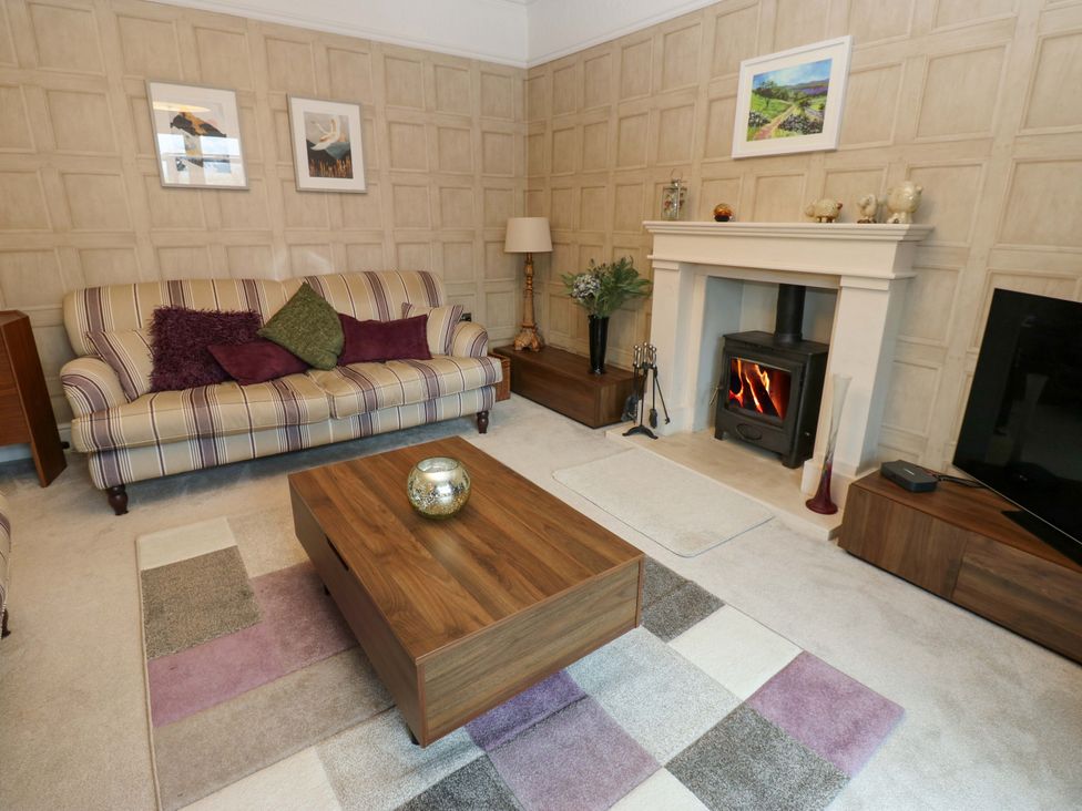 A living room with a sofa, coffee table and fireplace at Langcliffe House, Kettlewell