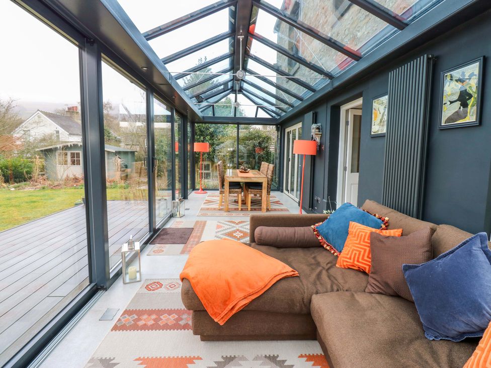 A conservatory with a sofa and dining area at Langcliffe House Kettlewell