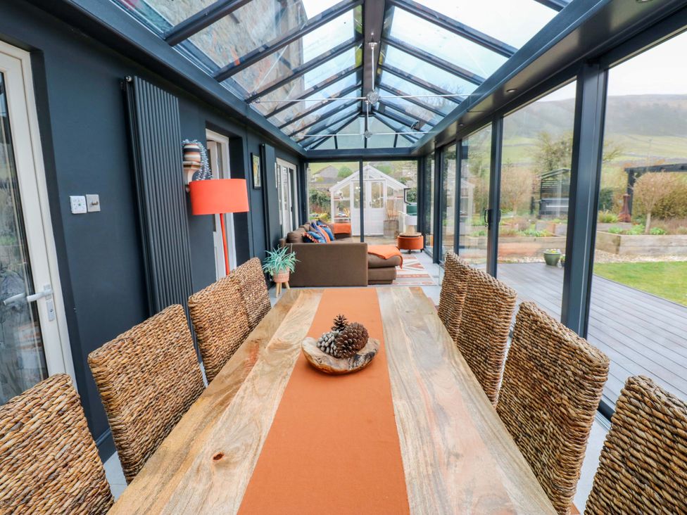 A conservatory with a dining table and chairs at Langcliffe House, Kettlewell