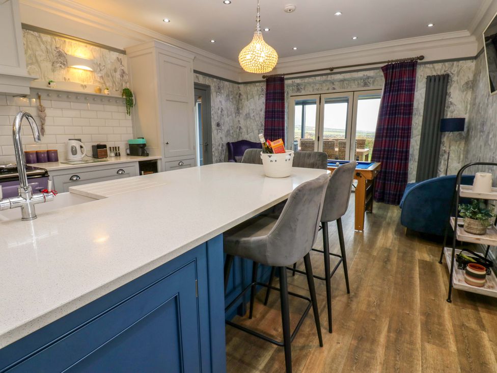 A kitchen with an island, stools and appliances at Langcliffe House Kettlewell