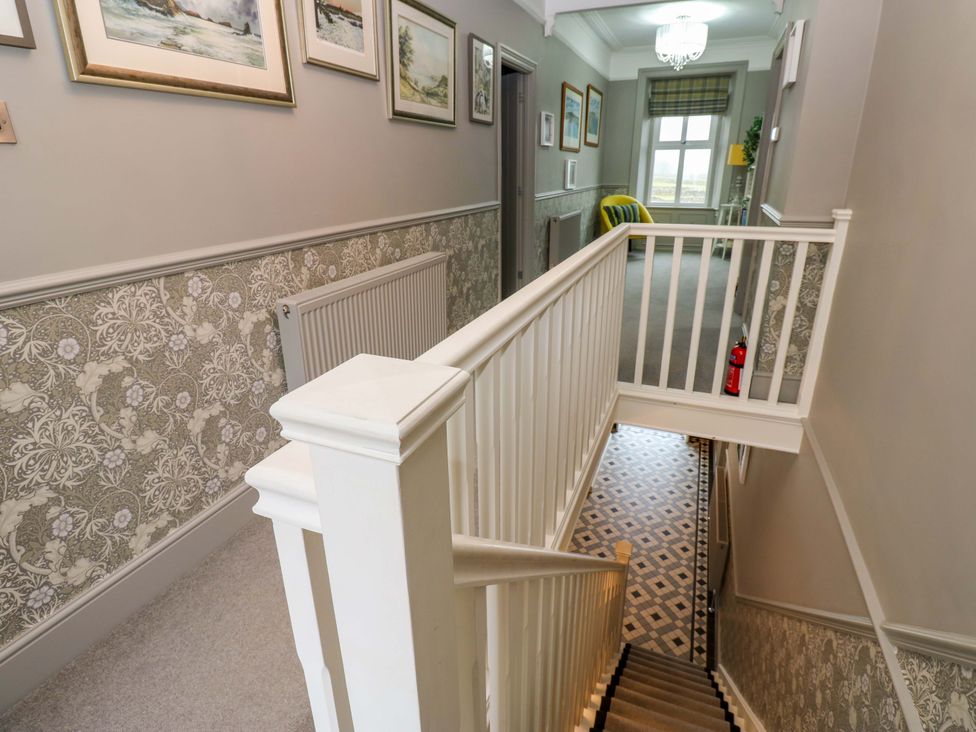 A hallway with a staircase and wall artwork at Langcliffe House Kettlewell