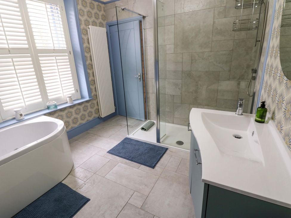 A bathroom with a bathtub, shower, sink, and towel rack at Langcliffe House, Kettlewell