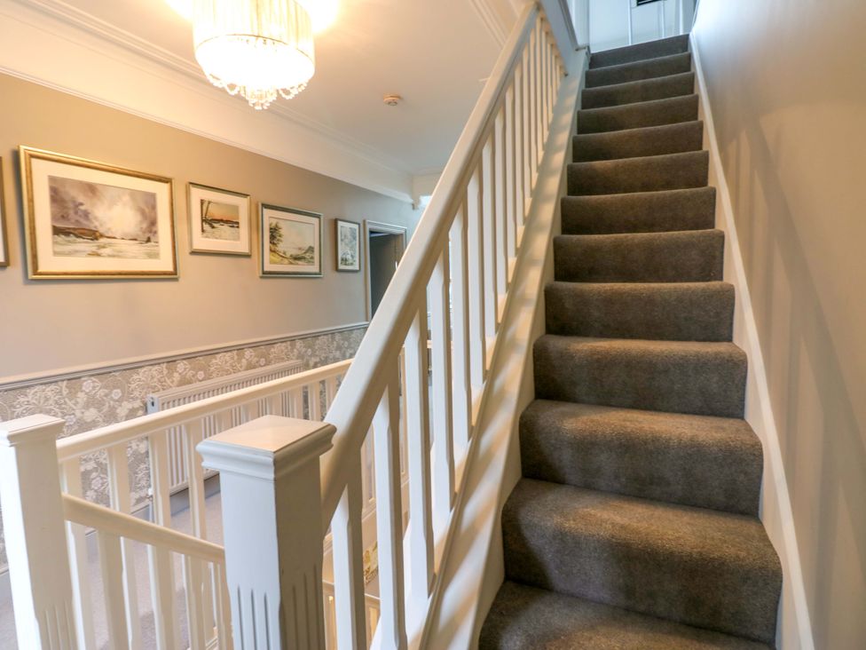 A hallway with stairs and pictures on the wall at Langcliffe House Kettlewell