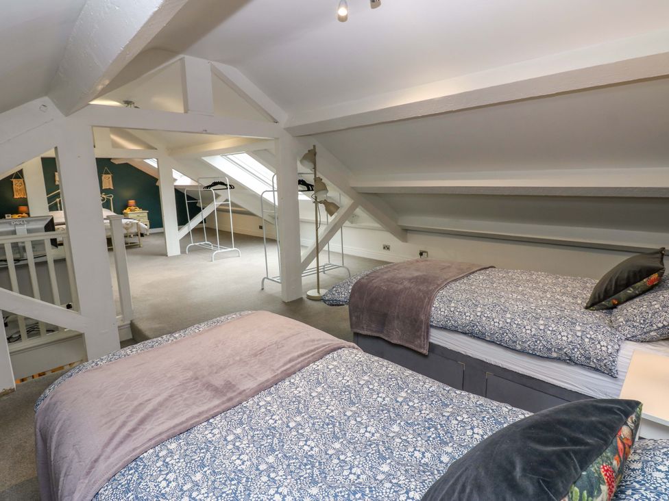 A bedroom with two beds and a clothing rack at Langcliffe House, Kettlewell