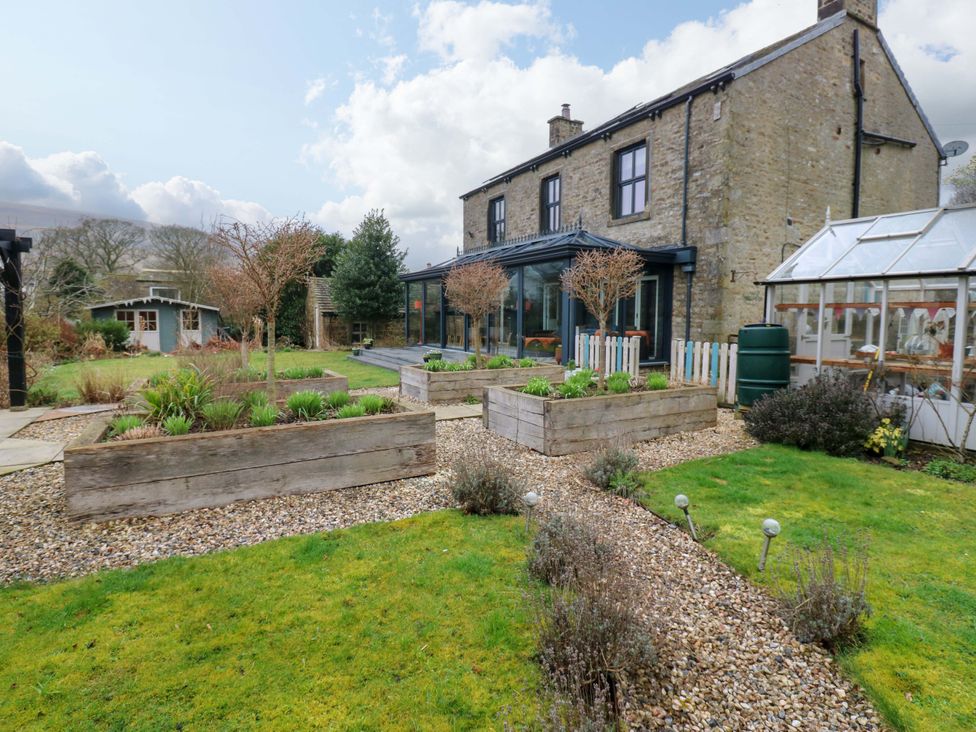 A garden with flower beds and a house at Langcliffe House Kettlewell