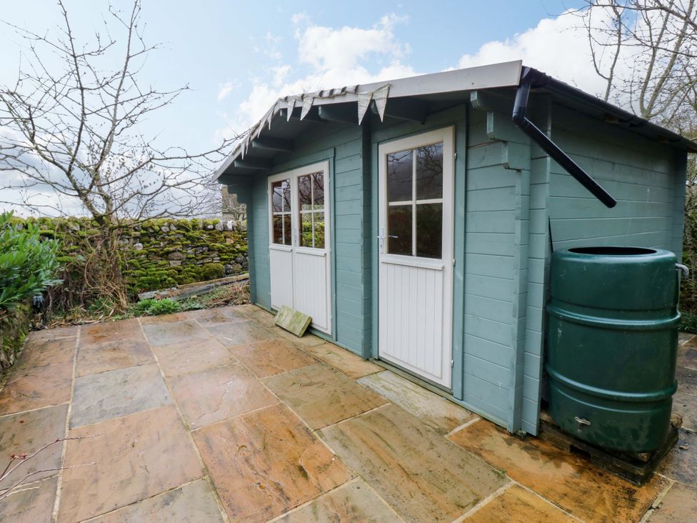 A garden shed with windows and a water butt at Langcliffe House Kettlewell