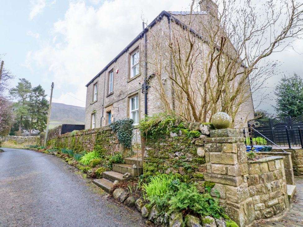 A house with stone walls and greenery at Langcliffe House in Kettlewell
