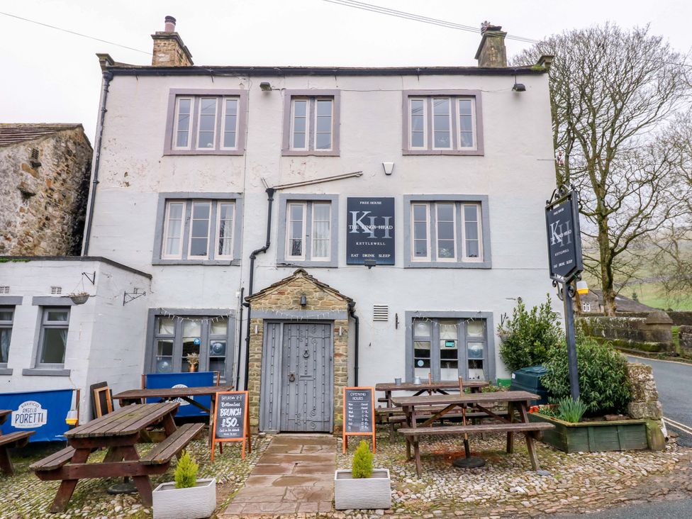 An exterior view of a pub with tables and a sign at Langcliffe House Kettlewell