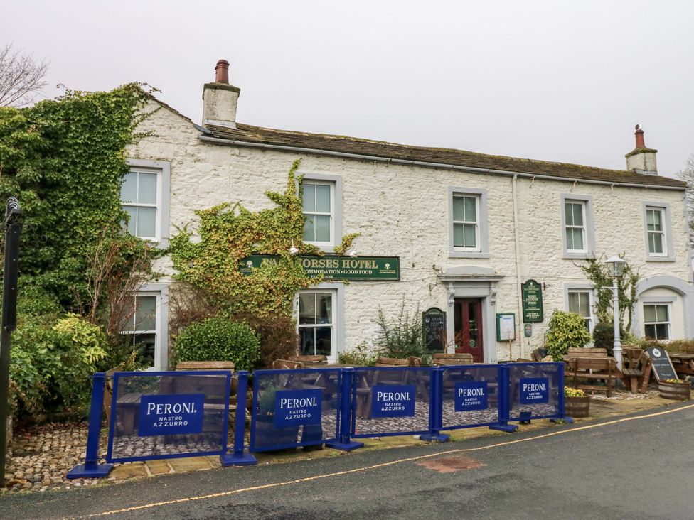 A hotel exterior with seating area and signage at Horses Hotel in Kettlewell