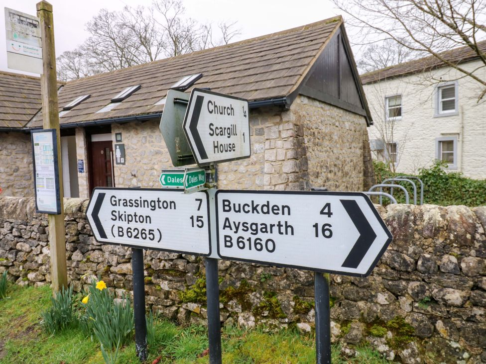 Road signs indicating directions to Grassington, Buckden, and Scargill House at Langcliffe House Kettlewell