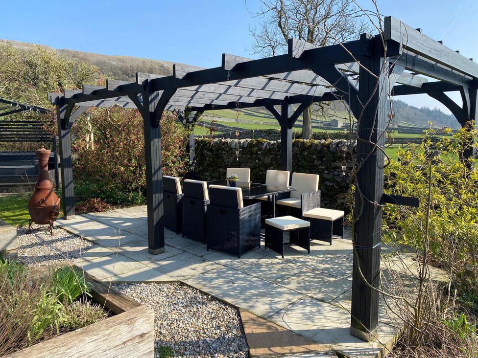 An outdoor seating area with a table and chairs at Langcliffe House in Kettlewell