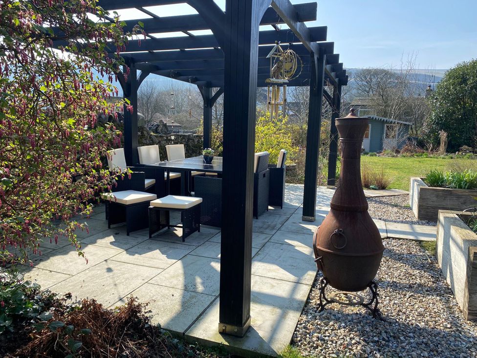 A garden with a table and chairs under a pergola at Langcliffe House in Kettlewell