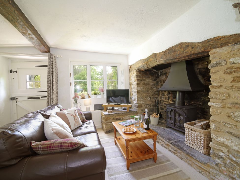 A living room with a fireplace and sofa at Lavender Cottage in Bourton, Dorset