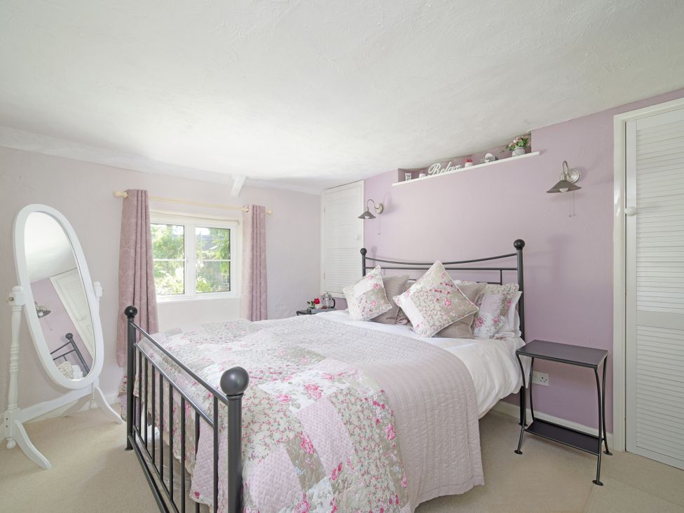 A bedroom with a bed and mirror at Lavender Cottage in Bourton, Dorset