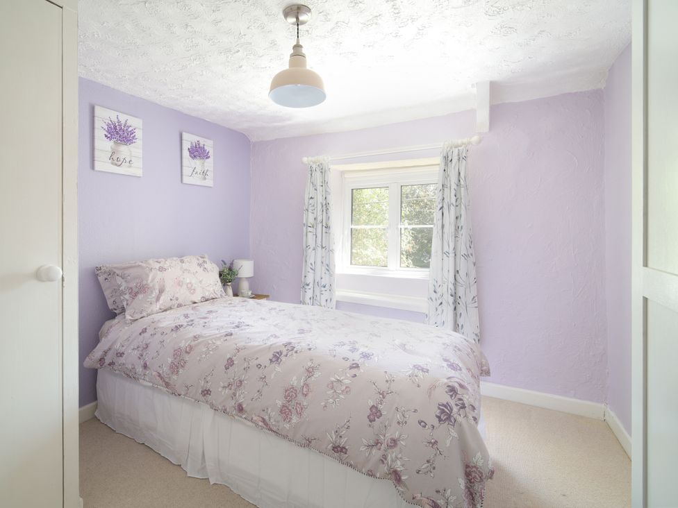 A bedroom with a bed and window at Lavender Cottage in Bourton, Dorset