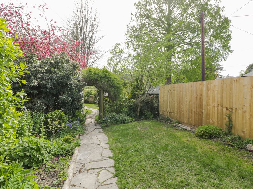 A garden with a pathway and various plants at Lavender Cottage in Bourton, Dorset