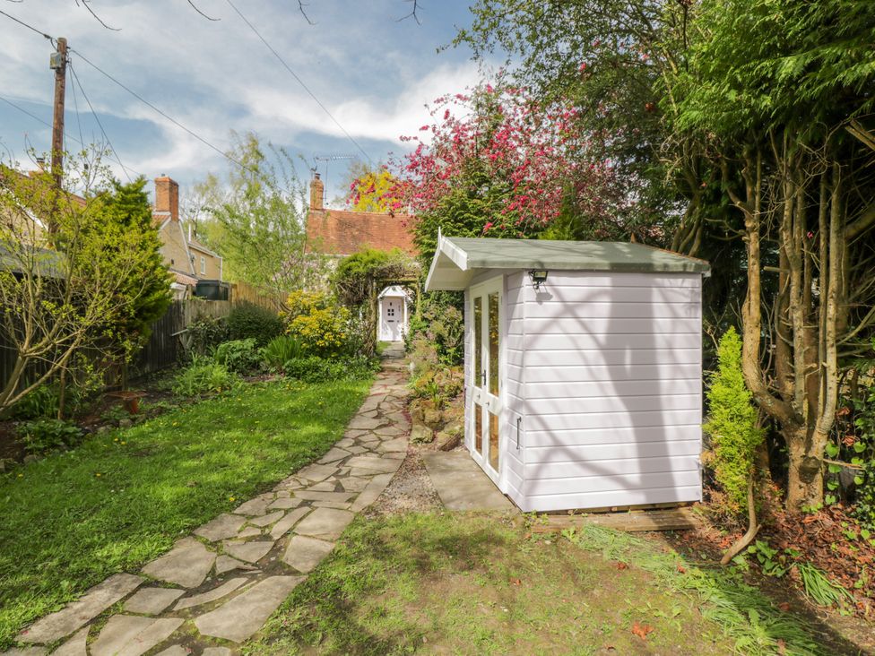 A garden with a pathway and a shed at Lavender Cottage in Bourton, Dorset