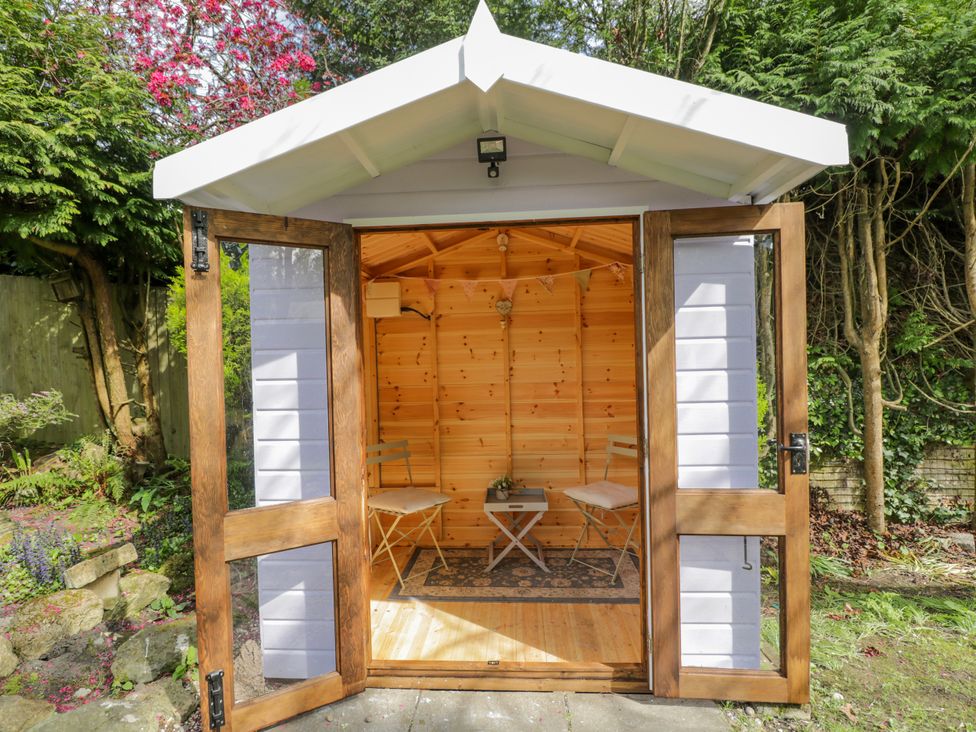 A garden room with wooden doors and furniture at Lavender Cottage in Bourton, Dorset