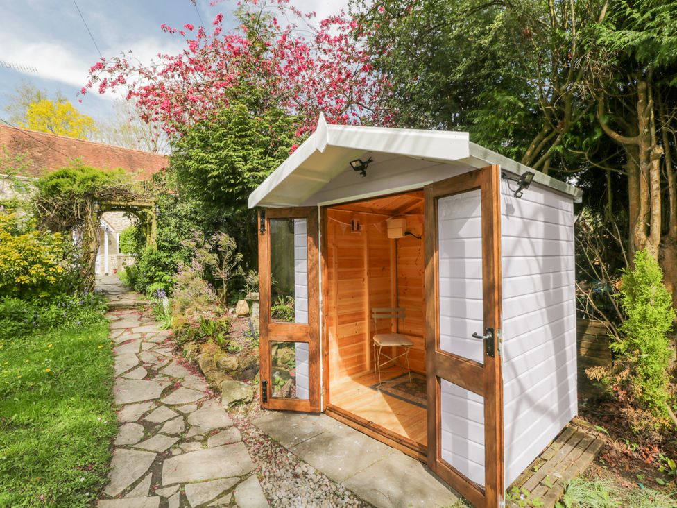 A garden shed with a chair and stone path at Lavender Cottage in Bourton, Dorset