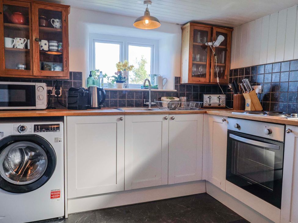 A kitchen with appliances including a washing machine and microwave at 2 Oak Tree Cottages Marshwood Nr. Hawkchurch