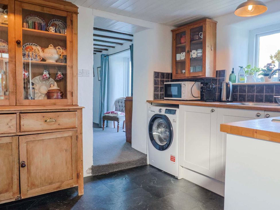 A kitchen with a washing machine and microwave at 2 Oak Tree Cottages Marshwood Nr. Hawkchurch