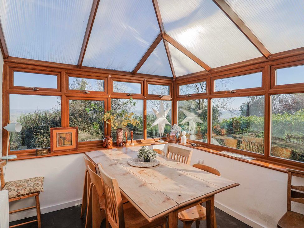 A conservatory with a wooden table and chairs at 2 Oak Tree Cottages in Marshwood Nr. Hawkchurch