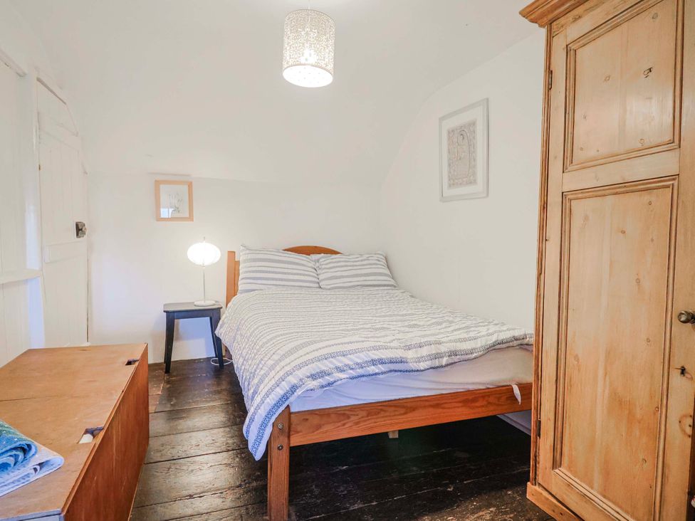 A bedroom with a bed and nightstand at 2 Oak Tree Cottages Marshwood Nr. Hawkchurch
