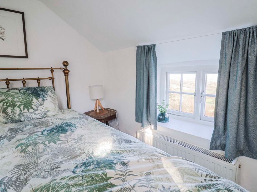 A bedroom with a bed, lamp, and window at 2 Oak Tree Cottages Marshwood Nr. Hawkchurch