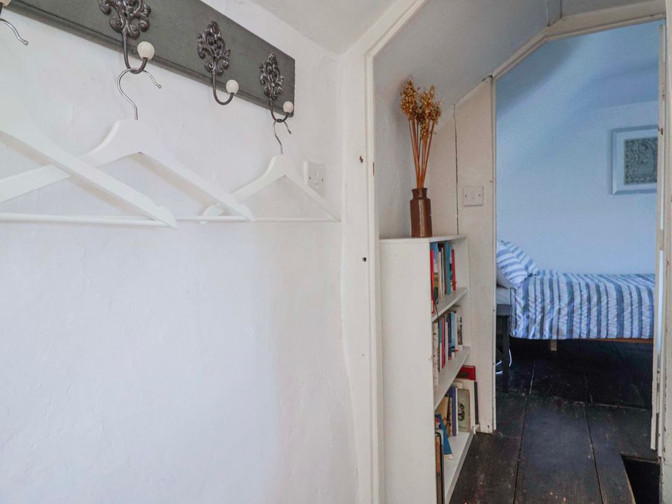 A hallway with a bookshelf and coat hooks at 2 Oak Tree Cottages Marshwood Nr. Hawkchurch