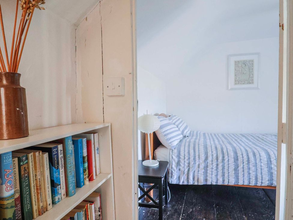 A bedroom with a bed and bookshelf at 2 Oak Tree Cottages, Marshwood Nr. Hawkchurch