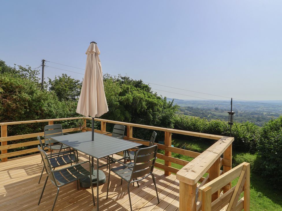 An outdoor space with a table and chairs under an umbrella at 2 Oak Tree Cottages in Marshwood Nr. Hawkchurch