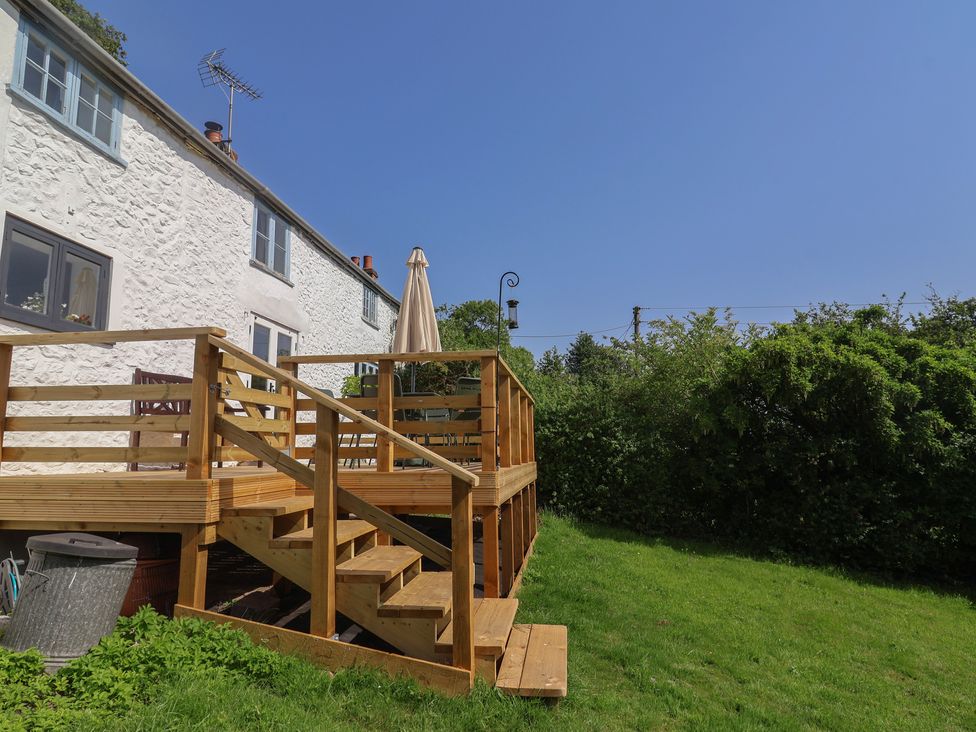 An outdoor area with a wooden deck and umbrella at 2 Oak Tree Cottages in Marshwood Nr. Hawkchurch