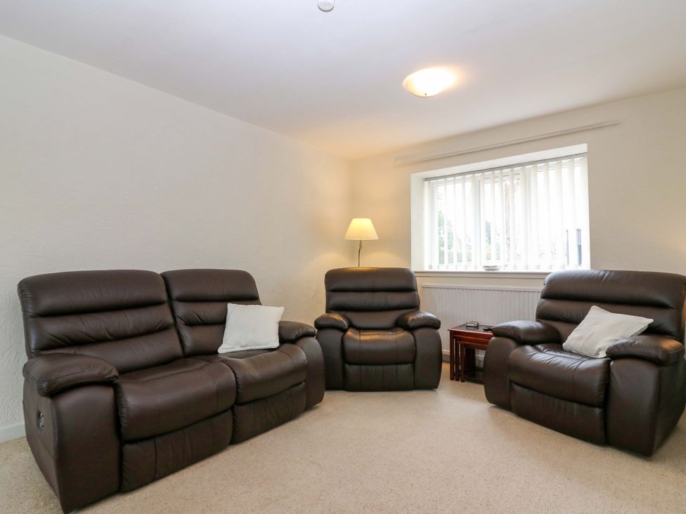 A living room with three recliner chairs and a lamp at Parkhill in Dairsie