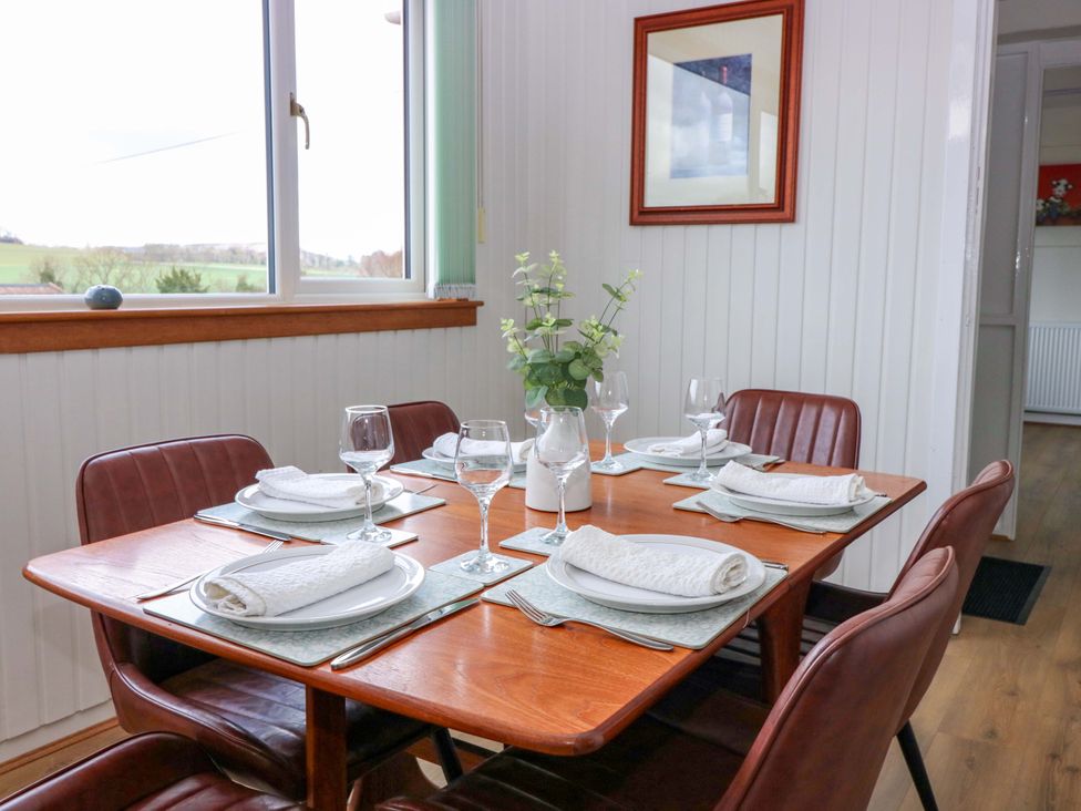 A dining room with a wooden table set for six at Parkhill in Dairsie
