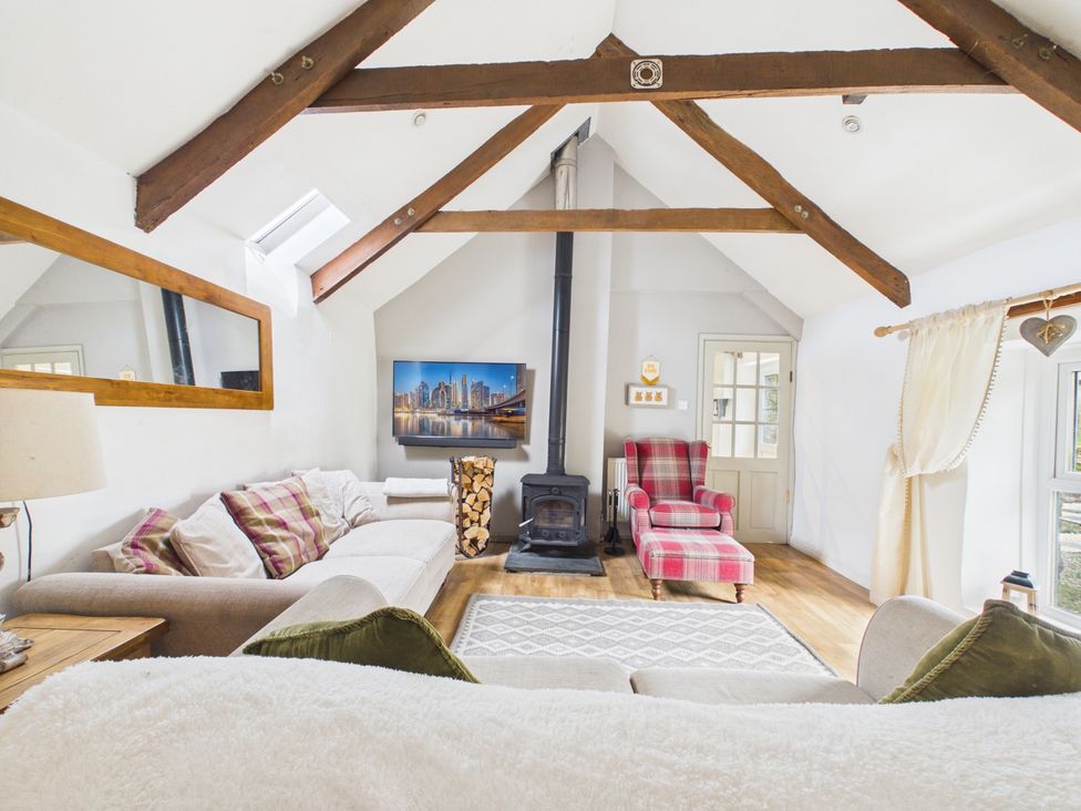 A living room with a sofa and a stove at Tor Farm in Advent near Camelford