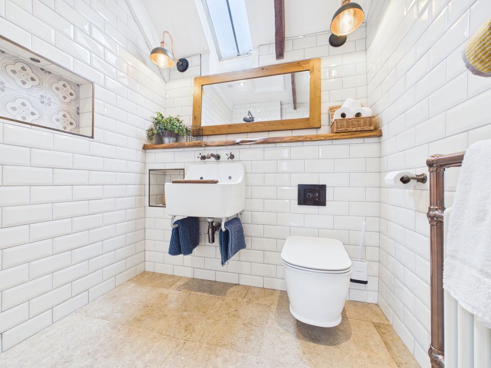 A bathroom with a toilet, sink, and mirror at Tor Farm in Advent near Camelford