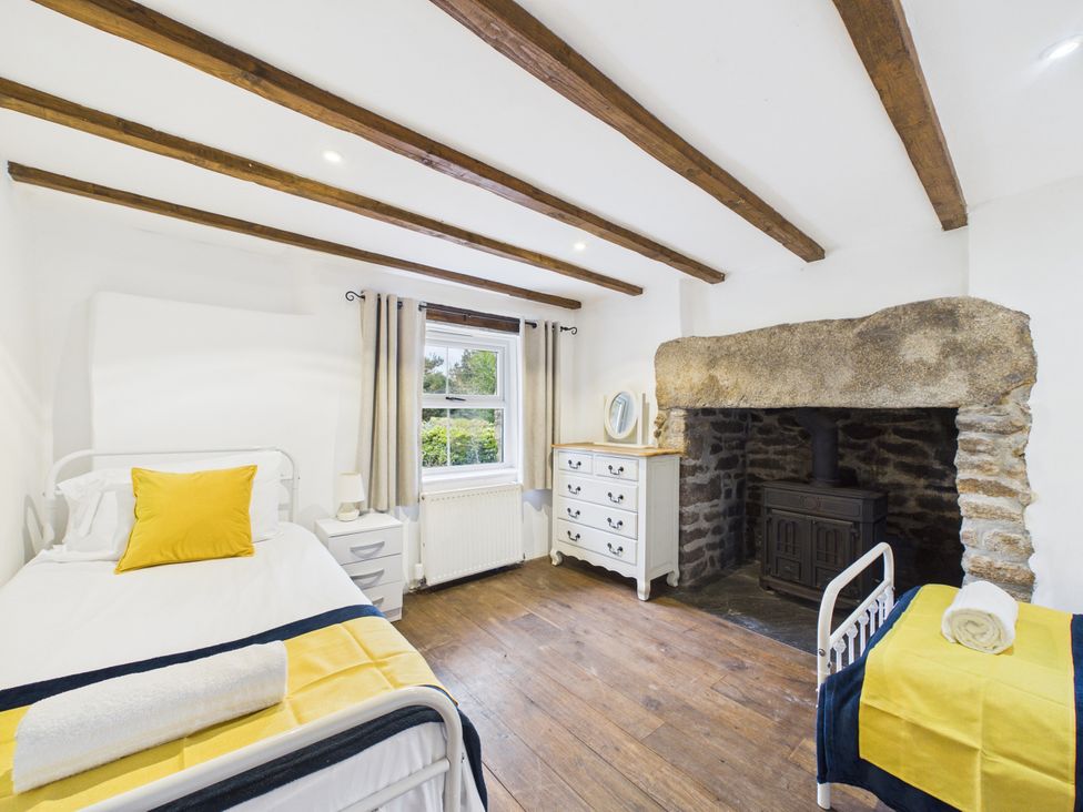A bedroom with two beds and a fireplace at Tor Farm in Advent near Camelford
