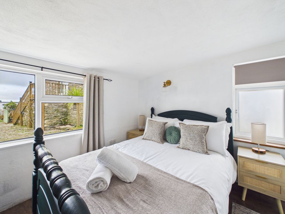 A bedroom with a bed and windows at Tor Farm in Advent near Camelford