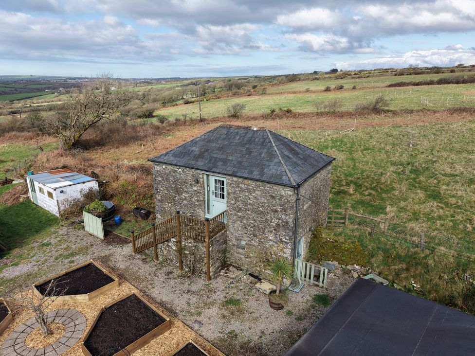 A stone building with stairs and deck surrounding a garden area at Tor Farm Advent near Camelford