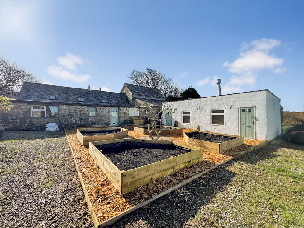 A garden with raised beds and a building at Tor Farm in Advent near Camelford