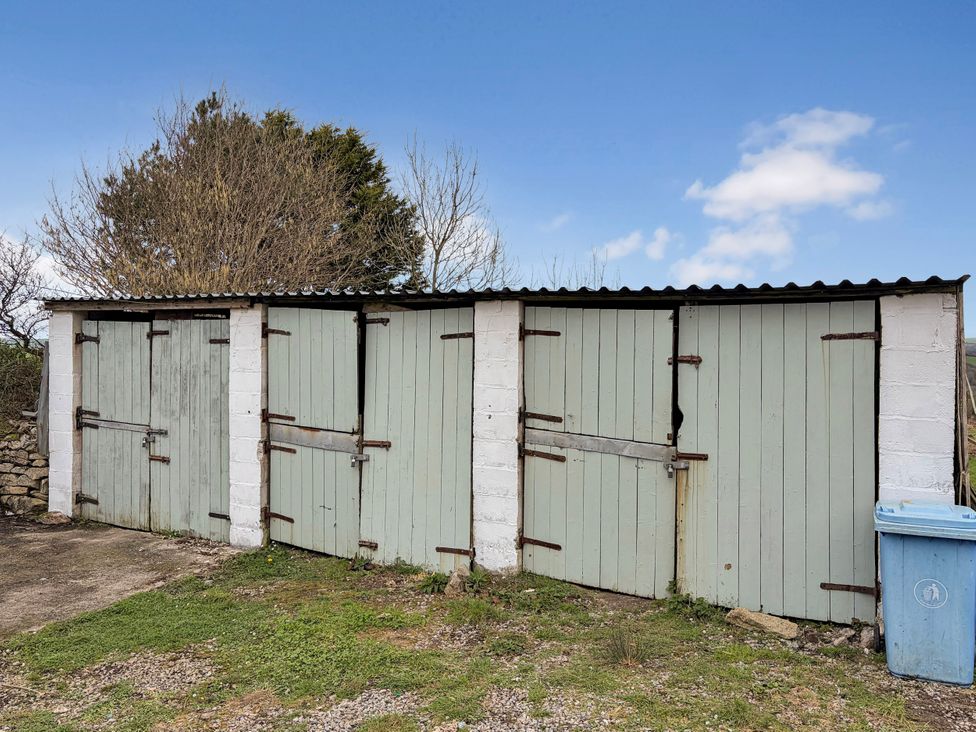 A row of sheds with doors and a blue bin at Tor Farm Advent near Camelford