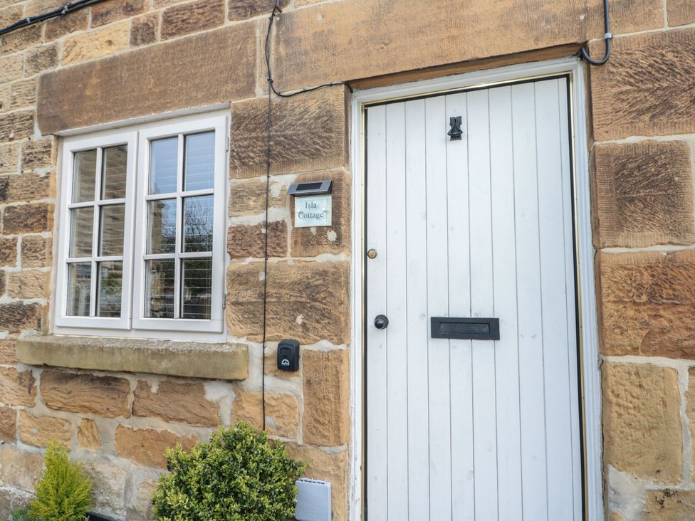 An entrance door with a window and nameplate at Isla Cottage