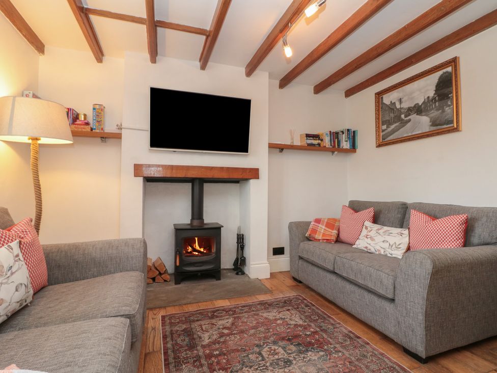 A living room with a television on the wall and a fireplace at Isla cottage