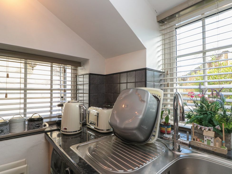 A kitchen with a sink, kettle, toaster, and storage containers at Isla cottage 